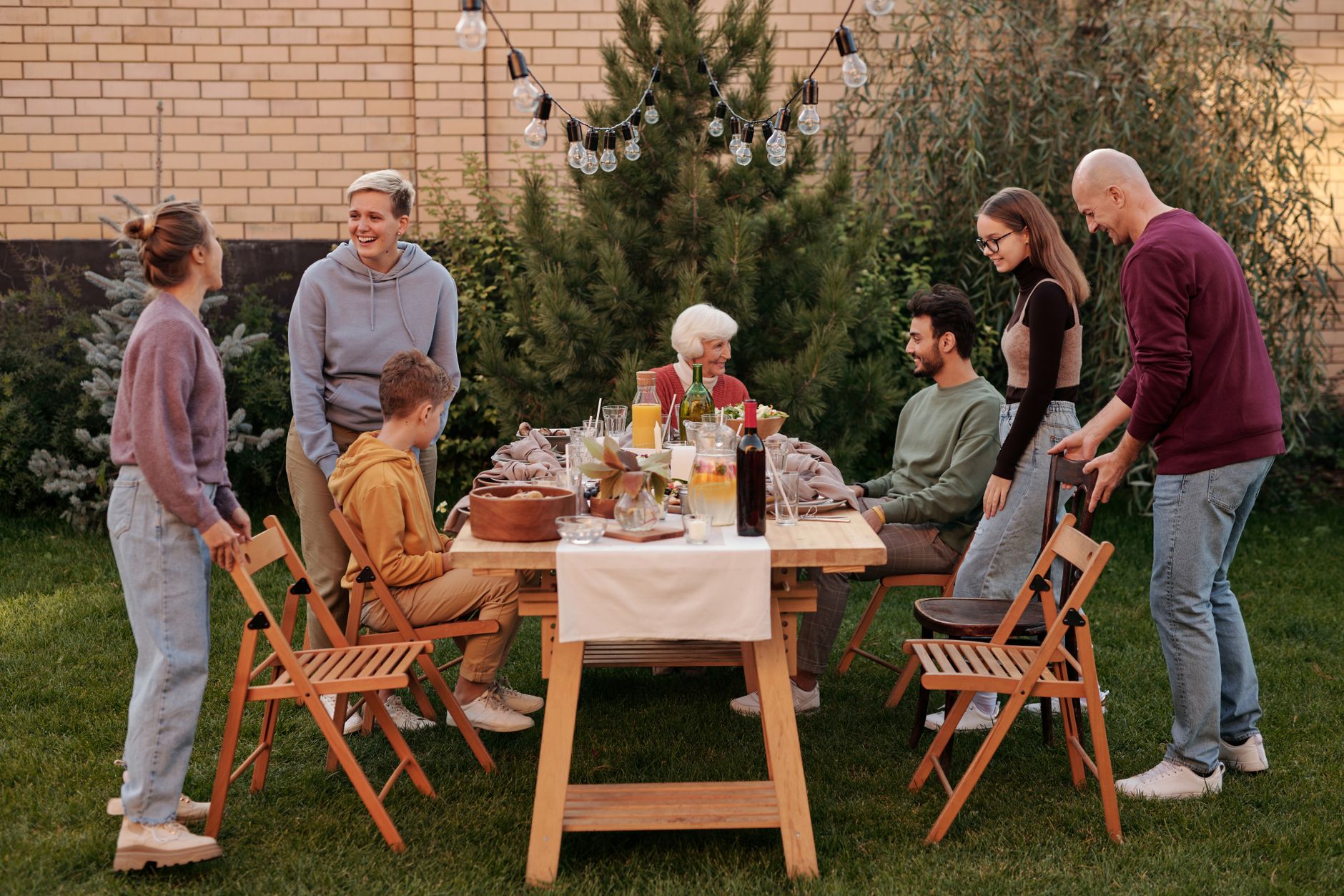 Several generations gathered around an outdoor dining table under string lights.